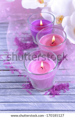 Beautiful colorful candles and  orchid flowers, on color wooden background