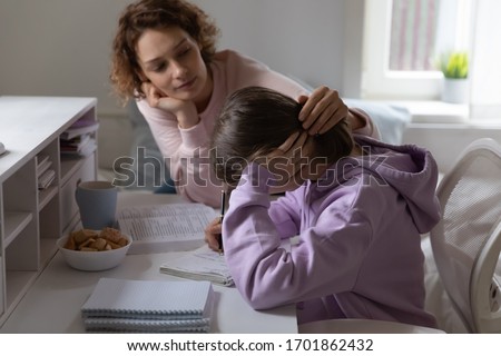 Loving mother supporting tired teenage daughter study together at home. Worried young parent mom helping comforting sad teen encouraging school girl having difficulty with education learning at home. Royalty-Free Stock Photo #1701862432