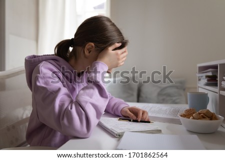 Tired bored teenage kid girl school student feeling headache or fatigue doing homework at home. Exhausted depressed sick teenager studying alone worried about difficult education problems concept. Royalty-Free Stock Photo #1701862564