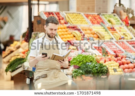 Portrait of bearded man calling supplier while selling fresh fruits and vegetables at farmers market, copy space