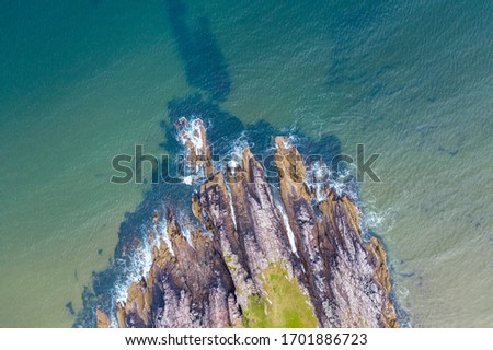Blue ocean waves crashing against rocky cliffs  - aerial top down view. Firemore Beach in the Northwest Highlands of Scotland