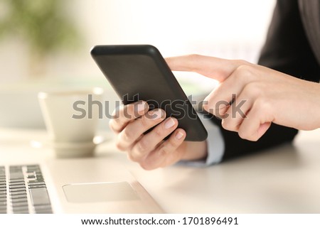 Cloe up of executive woman hands checking smart phone sitting on a desk at office