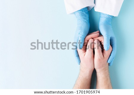 Doctor's hands in gloves holding man's hands. Medical background with copy space. Care concept.