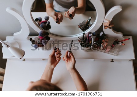 Top view of hands of caucasian girl with mascara in front of mirror