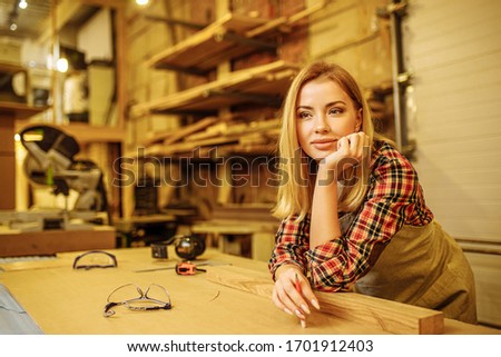 side view on beautiful woman after work, female work as carpenter in factory. stand next to desk, think