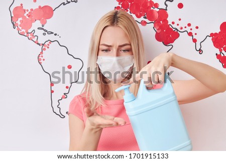 young caucasian woman in medical mask during COVID-19 epidemic, world map with red marks in the background, chinese and european global problems. showing coronavirus spread