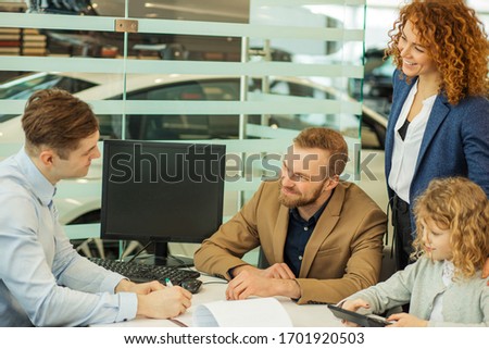young caucasian couple sign a contract of buying new car in dealership, sit at table with consultant