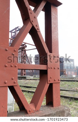 Distant portrait view of the 7th mine of the Essen Zollverein or mining group, with a textured brace in the foreground. Heavily industrial and architectural shot
