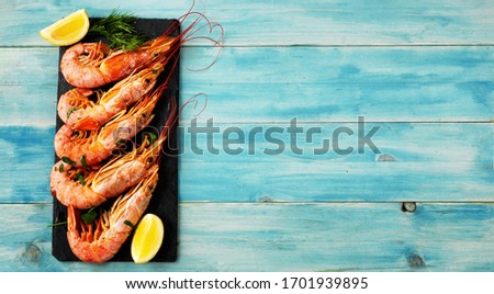 Top view of five big reg prawns on a slate palte and blue-green vintage background