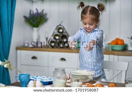 Little girl kneads dough in the kitchen at home. She cooks cookies with love