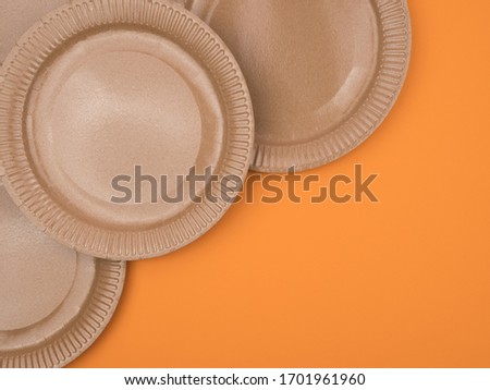 Brown cardboard plates on an orange background. Corner location. The view from the top.