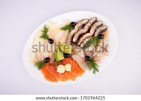 Fish plate with red fish, canned food and halibut, served with lime and dill and olives