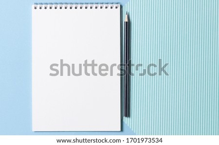 Flat lay of a female workplace. Open blank notebook and pencil on a blue striped background. Concept of planning and writing in notebook