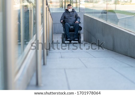 Disabled man on wheelchair wearing medical face mask for coronavirus protection.