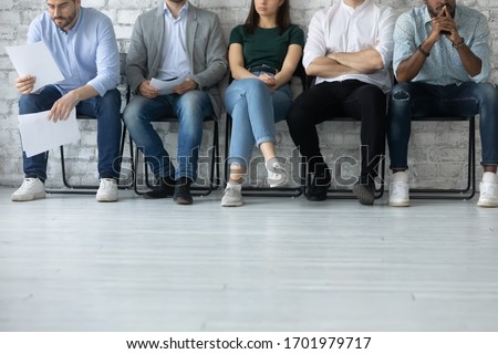 Close up of bored diverse multiracial job candidates sit in queue line feel anxious wait for interview, stressed multiethnic applicants get ready for work recruitment talk, employment concept Royalty-Free Stock Photo #1701979717