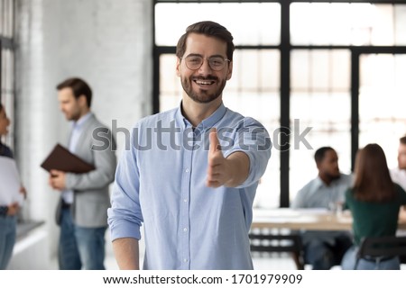 Smiling young Caucasian businessman stretch hand welcome new employee or worker at workplace, happy European male boss or CEO greeting meeting newcomer in office, employment concept Royalty-Free Stock Photo #1701979909