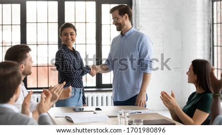 Smiling businessman shake hand of overjoyed Indian female newcomer at office meeting, diverse colleagues applaud to male employer handshake excited biracial woman worker, greeting with job promotion Royalty-Free Stock Photo #1701980896