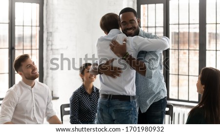 Happy diverse young people hug show support and understanding participate in counseling session together, smiling male patients embrace feel supportive engaged in psychological training or therapy Royalty-Free Stock Photo #1701980932