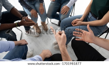 Top view close up of diverse colleagues sit in circle participate in group session or psychological therapy together, multiracial young people engaged in teambuilding activity or training in office Royalty-Free Stock Photo #1701981877