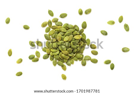 Isolated stack of toasted hulled pumpkin seeds on white background seen from atop, some seems are displaced around the stack