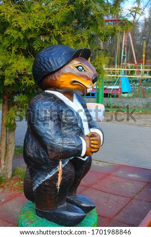 Vertical picture of a wooden figure of a beaver character in a black jacket and hat