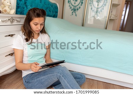 serious, business, young, pretty girl sitting near bed in bright room and looking at tablet working 