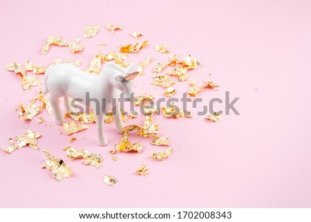 White unicorn and golden glitter over the pink background. Magic surreal, fairy tale style. Minimal composition