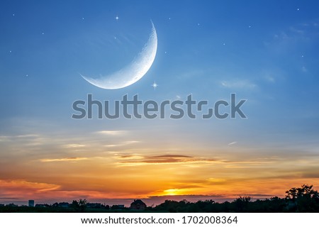 Moon in bright clouds of sunset sun . New moon , moon in the blue sky new moon in the clouds  Royalty-Free Stock Photo #1702008364