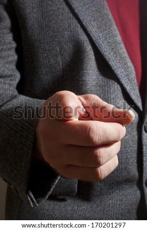 A man in a suit hand gesturing an index finger point 