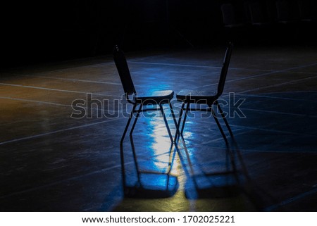 Two chairs on the stage with blue lights.