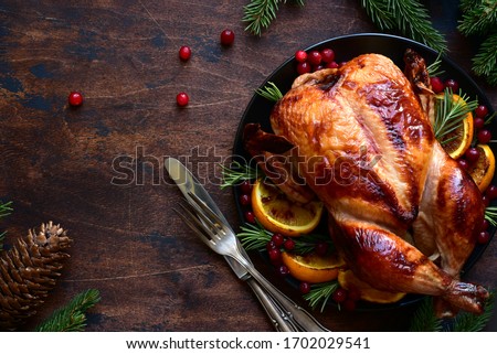 Roasted chicken with oranges ,rosemary and cranberries on a christmas table. Top view with copy space. Royalty-Free Stock Photo #1702029541