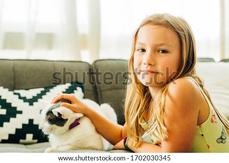 Little Girl Petting Cat on Sofa