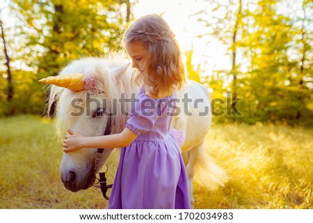 Girl in purple dress hugging white unicorn horse. Dreams come true. Fairy tale.