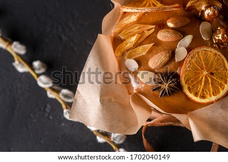 Easter cake on a dark background , beautiful scenery, caramelized , decorated dried fruits, nuts, soft focus, wrapped in baking paper