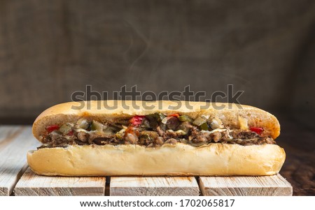 Philly cheese steak with steam on wooden surface Royalty-Free Stock Photo #1702065817