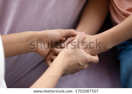 Close up african american mother and teen daughter hand holding together. Caring family spend time in private in living room at home. Young mom and girl create sweet bonding. Royalty-Free Stock Photo #1702087507
