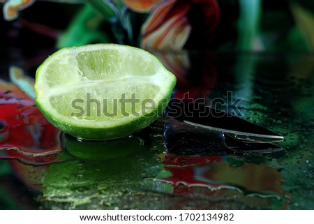 A sliced lime with a small knife shot macro with a reflection and water drops.