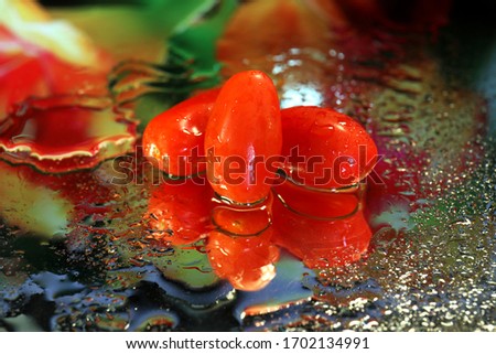 Delicious ripe red tomatoes on a mirror reflecting the vivid colours and water drops.