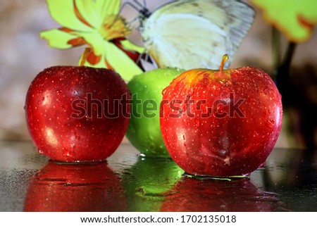 Apples: Delicious ripe apples of red and green together on a wet mirror with a bright coloured background.