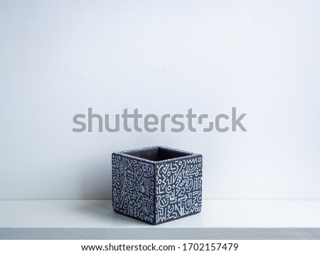 Cactus pot. Concrete pot. Empty black with modern graphic pattern geometric concrete planter on white wooden shelf isolated on white wall background.