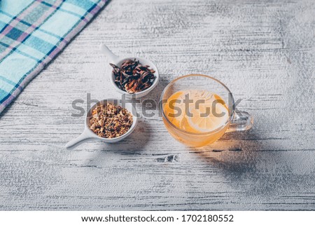 Set of tea herbs and orange colored water on a gray background. high angle view.