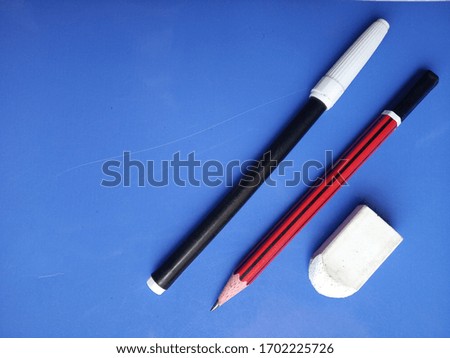 still life minimal photo of pencils
 and white eraser on blue background wallpaper