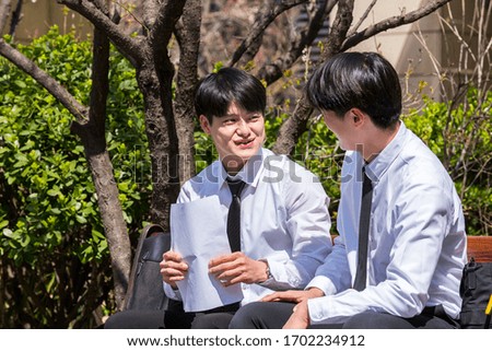 Two young business men are having a pleasant conversation sitting on a park van