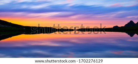 Banner, web page or cover template of couple in love by lake in mountains. silhouette sunset sky. Copy space and panoramic ratio