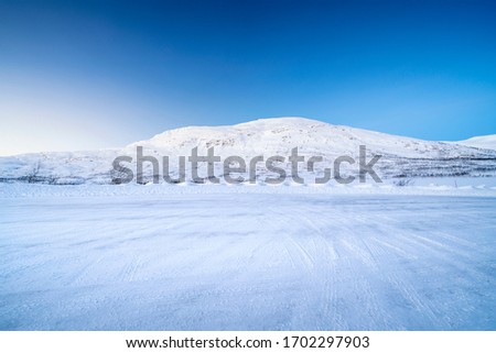  Icy road against snowcapped mountain Royalty-Free Stock Photo #1702297903