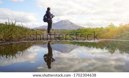 Effect flare light, Reflection in water Woman holding medium format camera and looking view Mountain landscape among cloudy in blue sky 