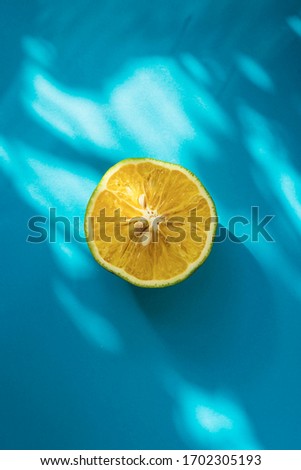 A photo of a sweet lime cut into half shot with natural lighting. Used a complementary colour as a background.  