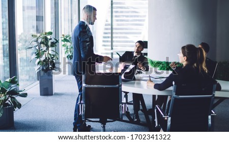 Successful leadership explaining monetary gain during together training at conference table, male and female professional colleagues research strategy during productive brainstorming in office