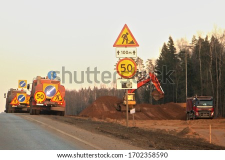 Road construction equipment, signs special vehicles on the construction site on roadside and forest background