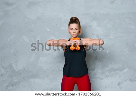 Young girl with dumbbells on a grey background. Concept fitness sport training lifestyle
